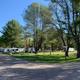 Wide view of multiple RVs and campground roads among trees — good overall site overview demonstrating space and setting. Sourced from the site gallery/homepage images.