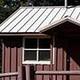 Cabin with red siding in front of conifer forest