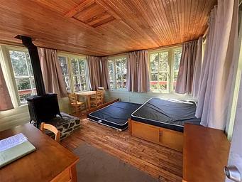 Inside of cabin with trundle bed, desk, table, and propane heater.