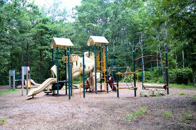 Playground equipment in a wooded setting — shows family-friendly recreation facilities located on the campground property (displayed in the site's images).