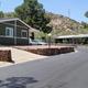 Another street/lot view showing a manufactured home, driveway and neighborhood paving — complements other home-focused images for the property gallery (from homes-for-sale content).