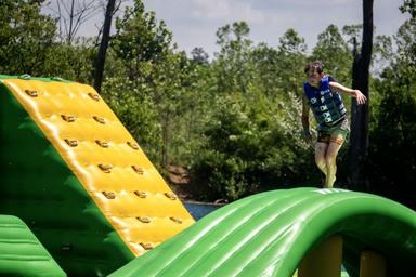 Indian Springs Campground & Water Park - Family enjoying the new Splash Springs Floating Water Park with water slide, beach area, and scenic fishing lakes in a serene forest setting. Perfect for camping, fishing, and water fun near Fort Wayne.