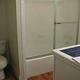 Cabin bathroom with tub shower combination with glass door, toilet and single bowl sink. Tight for wheelchair access.