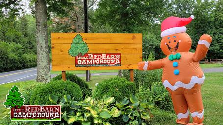 Entrance sign photo with landscaping and seasonal inflatable — useful exterior landmark/entrance shot confirming property identity on the campground site.