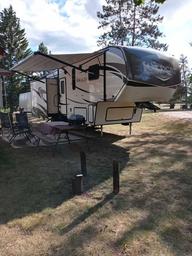Close view of an RV at a campsite with awning, chairs and outdoor setup — good for illustrating typical RV pitch space and site features (from the campsite page images).