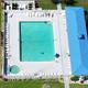 Aerial shot of the pool and adjacent building showing pool layout, surrounding deck chairs and spa — useful facility image (source: ‘Pool-aerial-Oct 2023’).