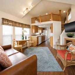 Interior living area of a cabin (kitchen, seating and loft stairs) — demonstrates the interior accommodations available at the resort (from the property gallery).