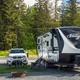 Travel trailer parked at a gravel RV site with picnic table, fire ring and vehicle — clear view of RV site layout and hookups. File is from the Seward 'waystostayphotos' images on the campground page.