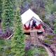 Aerial/drone-style view looking down at a single tent on its deck with surrounding trees and trail — good overview of campsite placement, deck and access path on the property (site context shows this view).