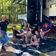 Group relaxing at an RV campsite with a large RV visible — useful photo of the campground’s RV pitches and site setup (trees, spacing, amenities).