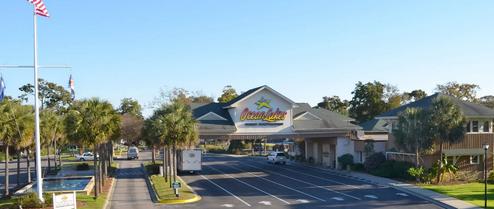 Main entrance drive with Ocean Lakes sign and approach road — establishes property entry and scale, from the campground homepage imagery.