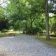 Gravel RV/campsite with picnic table, utility pedestal and mature trees — clearly a site photo from the ‘Sites’ page (shows typical pitch and setting).
