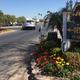Entrance drive and office sign with landscaped flowerbeds and RVs visible in the background — useful for showing arrival/office area and on-site RV parking (file from site homepage).