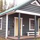 A wooden cabin with a porch in the woods