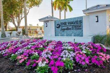 Entrance sign and landscaping with property name 'The Waves' clearly visible — taken from the site’s gallery and identifies the property entry.