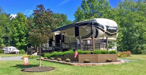 Close view of a full‑hookup RV on a prepared site with decking and landscaping — illustrates individual site quality (used as a campsite/hero image on the site).