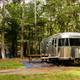 Airstream-style trailer and tent site in wooded setting — useful campsite overview demonstrating site types and wooded character of the campground.