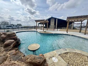 Pool area photo showing resort-style pool, pergolas and clubhouse beyond — highlights on-site recreation and amenities (visible on site gallery).
