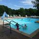 Photo of the heated outdoor pool with lounge chairs and surrounding trees — depicts a key on-site facility. Comes from the site's Facilities page, confirming it’s a campground amenity.