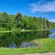 Wide lakeside view showing the farm’s pond, dock and tree-lined shore — clear scenic overview used on the homepage/gallery (https://tildenhillfarm.com/). Good aerial-like landscape shot of property grounds.