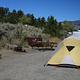 A view of junipers and sagebrush behind a yellow tent at campsite 3