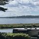 Scenic lake view with RV and greenery under a partly cloudy sky.