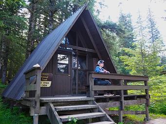 Person looking at scenery from railing of Mount Rynda Cabin exterior A Frame cabin