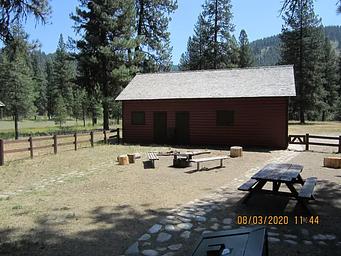 A fenced yard with a campfire ring and picnic tables.