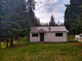 A small white cabin in a green field.
