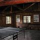 Ping-pong table in dimly lit large room with log rafters and benches.