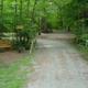 Pathway into wooded tent/RV sites (from Tent Site menu), showing campsite layout, tree cover and guest areas — useful for visitors evaluating pitches.