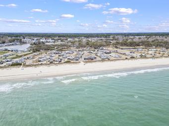 Aerial photo showing the campground strip along the beach and nearby facilities; useful as an overview of site layout and proximity to shore (source page: testimonials).