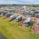 High-angle photo of lined RV sites along the lakeshore showing individual pads, hookups and landscaping — useful for showcasing RV accommodations (site home page image).