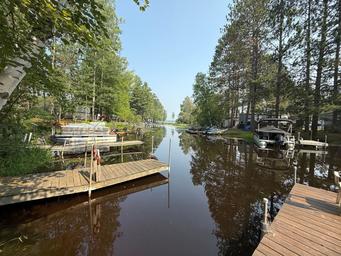 Wide waterfront/boat-dock panorama showing multiple docks and boats along a wooded channel — good aerial-style/overview of the property’s lake access and docks (background/hero image on site).