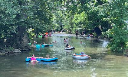 River scene with people floating and trees along the bank — depicts the on-property river/recreation (file labeled river-float on the campground site).