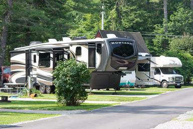 Row of RV sites with paved road, hookups and grassy pads — clear depiction of the campsite/RV pitch offering on the property (image named 'rvsites' on the site).
