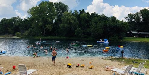 Beach/lake swim area showing shoreline, swimmers and floats — illustrates the campground's waterfront recreation (source: homepage beach image).