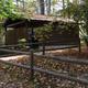 Exterior of a campground restroom/building set in woods — shows on-site facilities and their wooded setting (from Amenities page).