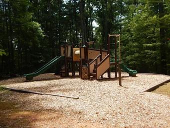 Children's playground surrounded with wood chips and nestled in the forest.
