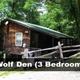 Exterior view of 'Wolf Den' (3 bedroom) cabin set in wooded surroundings with access ramp and fence — clearly a on-site cabin shown on the homepage catalog.
