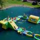 Aerial view of the resort’s swim pond with an inflatable Wibit play structure and surrounding lawn — matches the amenities imagery on the site (page: homepage/amenities) showing on‑site water recreation.