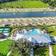 High, wide aerial view of the resort showing clubhouse, pool, pickleball/tennis courts, two large retention ponds and rows of RV pads—matches plan-your-stay page DJI aerial imagery of the property layout.