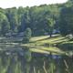 Lakeside view showing grassy slopes with multiple campsite/RV locations and tree buffer — useful alternative angle of the campground shoreline (gallery page).
