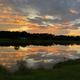 Scenic lakeside sunset reflection across the water — highlights the property's lake scenery and ambiance; from the 'Our Community' gallery on the site.