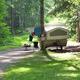 Campsite image with pop-up camper, site marker (#12), picnic table and access road — illustrates site amenities and grassy/wooded terrain.