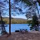 Lakeside picnic table and fire ring at a campsite — clear view of an individual campsite and waterfront setting.