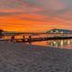 Sunset view of the sandy beach and main dock/pier with covered structure — good scenic shot of the campground waterfront and beach area (from the site homepage).
