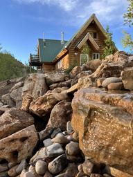 Hummingbird Cabin â log cabin with green roof perched above rocky canyon landscape at Zen Zion