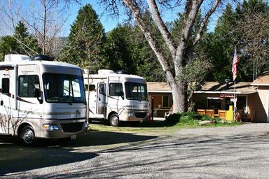 Gravel RV lot with multiple motorhomes and the office/building visible in background; from the park facilities page illustrating the main parking/office area and typical RV pitches.