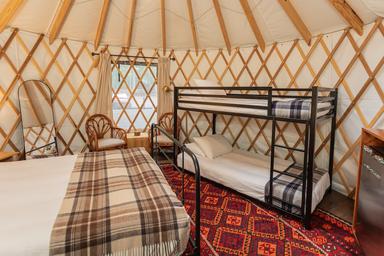 Inside a Roamstead yurt showing twin bunk beds and cozy mountain decor for families.